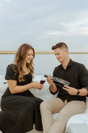 A couple sharing wine drinks on a boat during a romantic waterfront date.