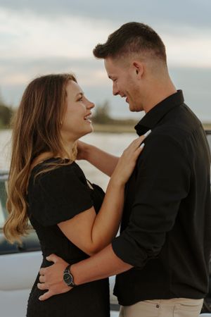 Couple sharing an intimate moment while embracing by the water at sunset.