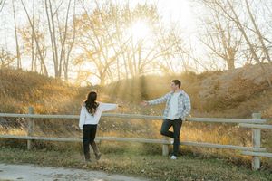 A couple enjoys a romantic sunset photoshoot in a rustic outdoor setting with golden light filtering through trees.