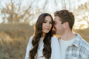 A couple shares romantic moments outdoors during a sunset engagement photo session in a natural setting.