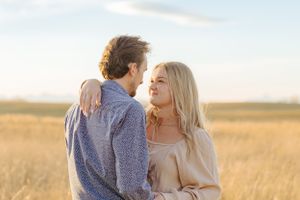 Intimate moment captured between couple in wheat field at golden hour.
