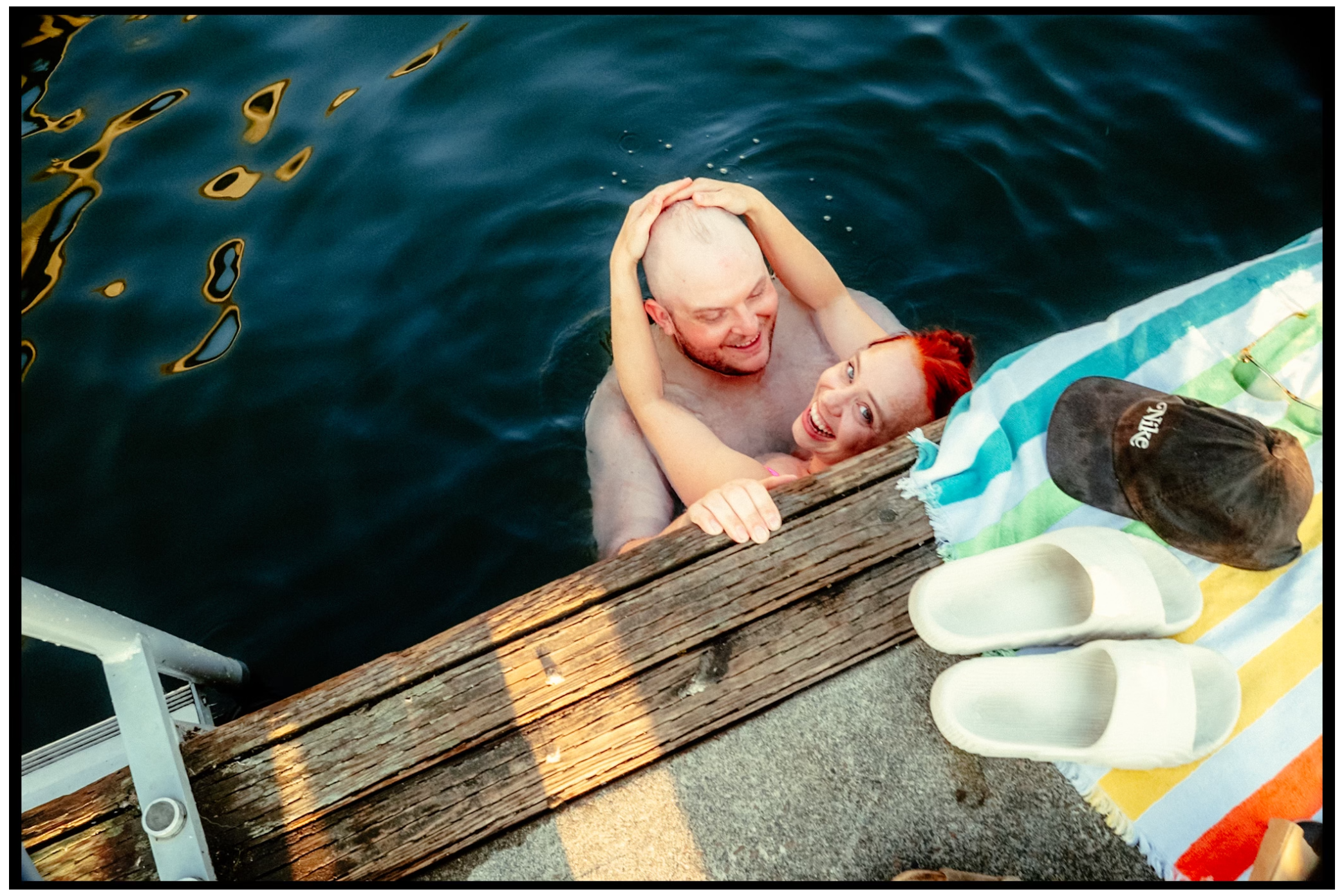 Swimmers climbing onto wooden dock with inflatable floats during summer gathering. Willamette River, Portland, OR