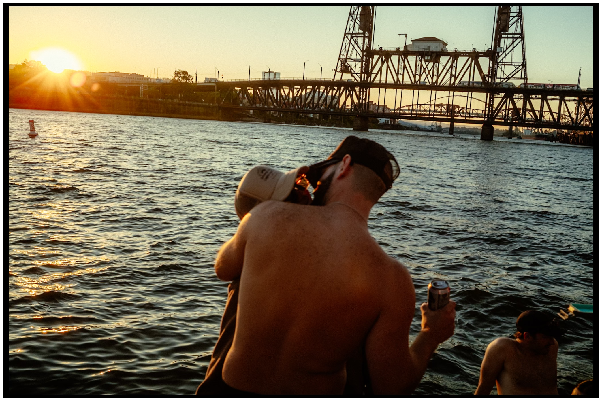 Swimmers enjoying sunset gathering beneath Portland's industrial bridge. Willamette River, Portland, OR