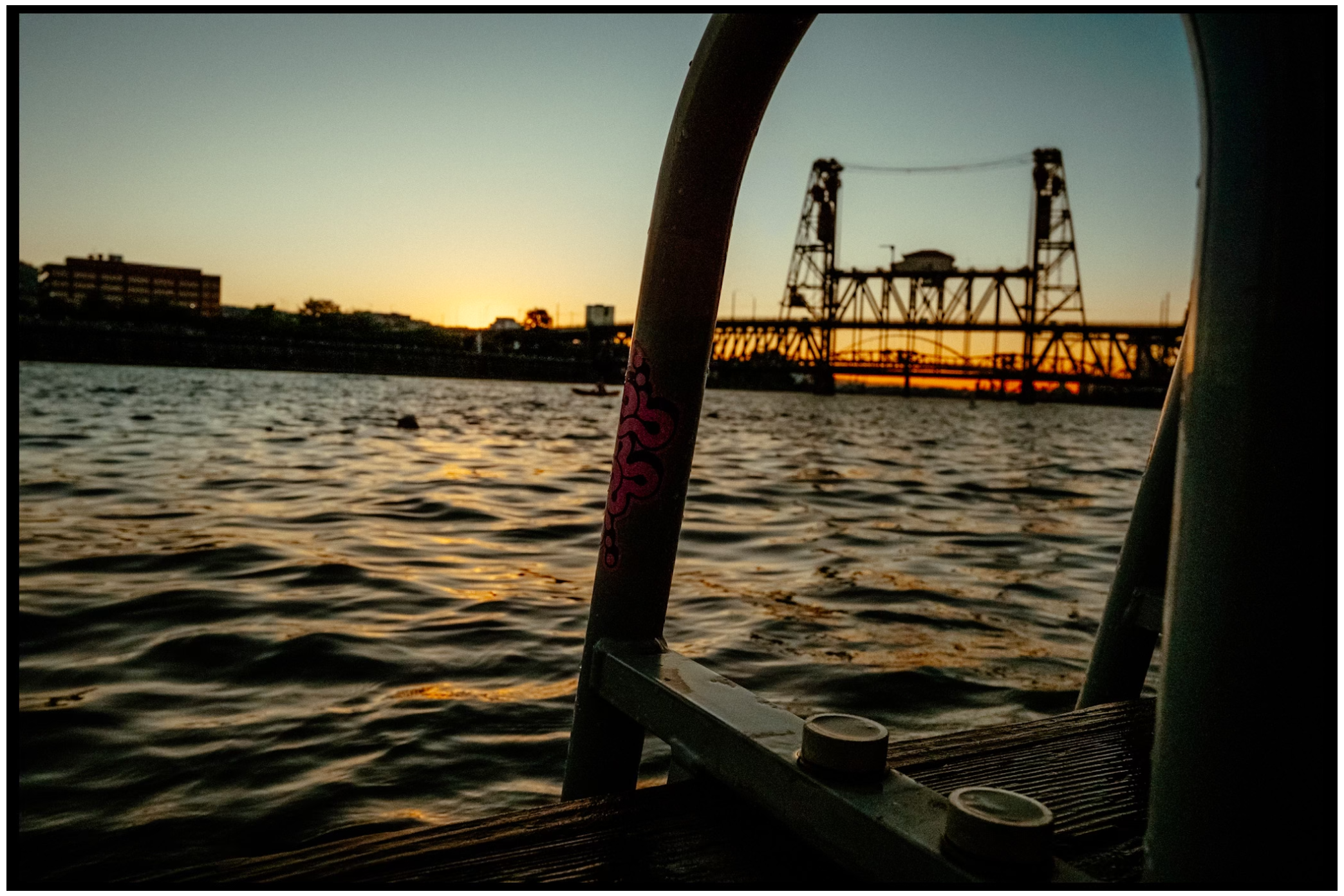 Steel bridge silhouetted against sunset over rippling water in Portland harbor. Willamette River, Portland, OR