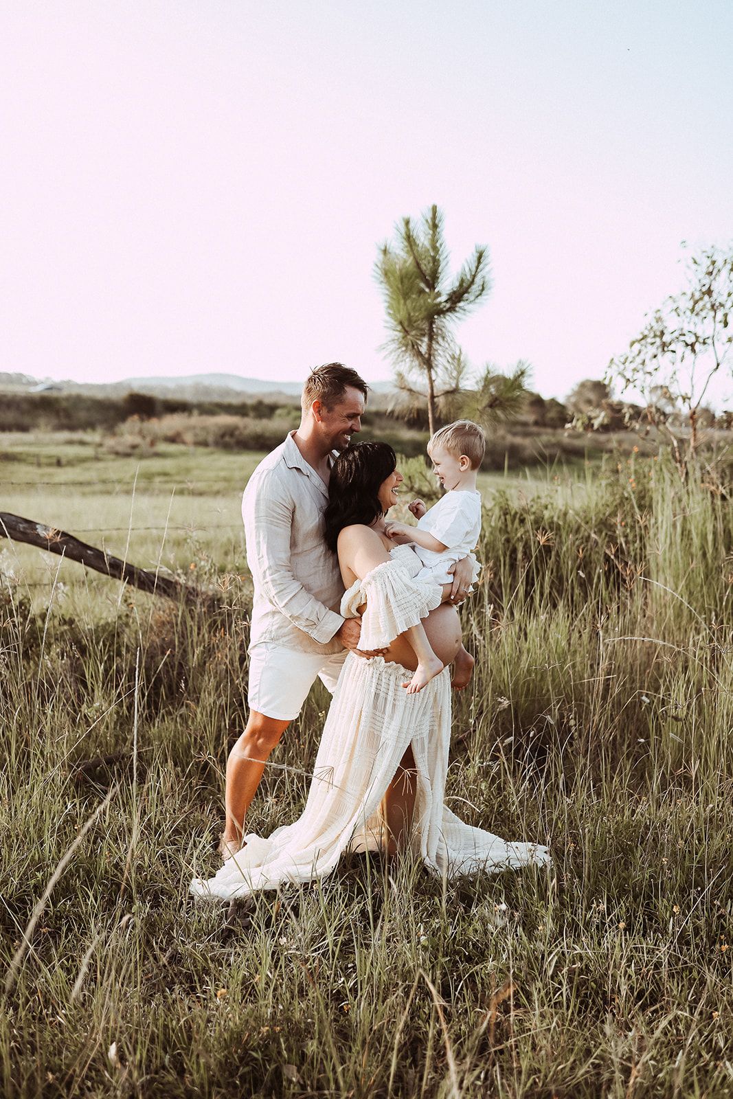 Family sharing an intimate moment together in a rustic field at sunset.