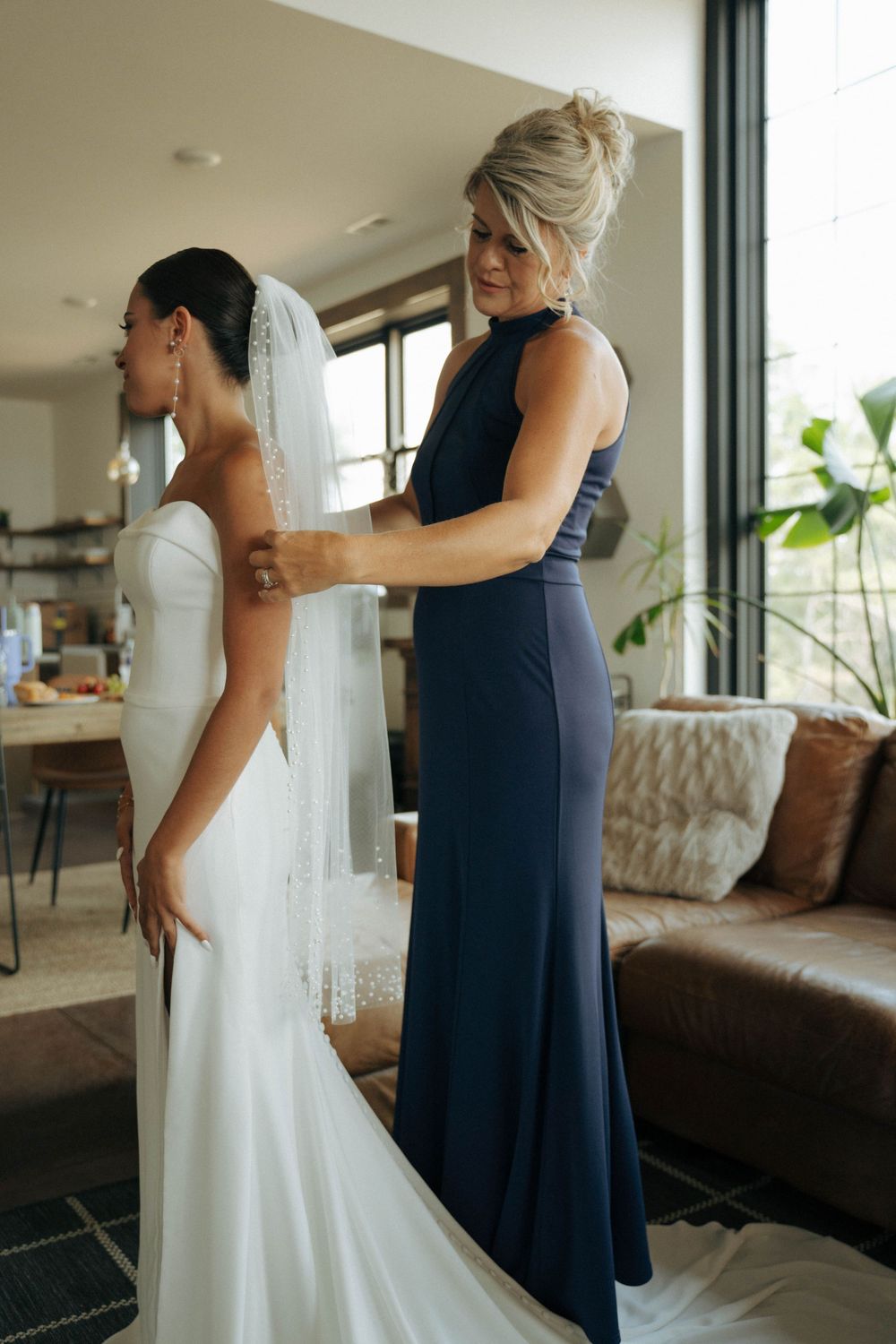 Final wedding dress adjustments being made in modern interior setting.