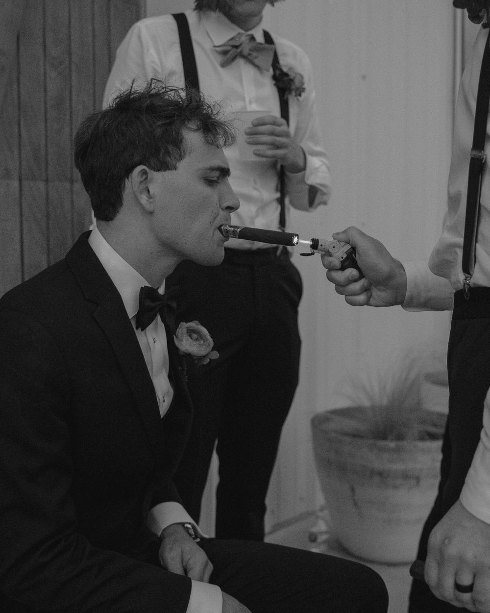 Black and white photo of someone lighting a cigar at a formal event.