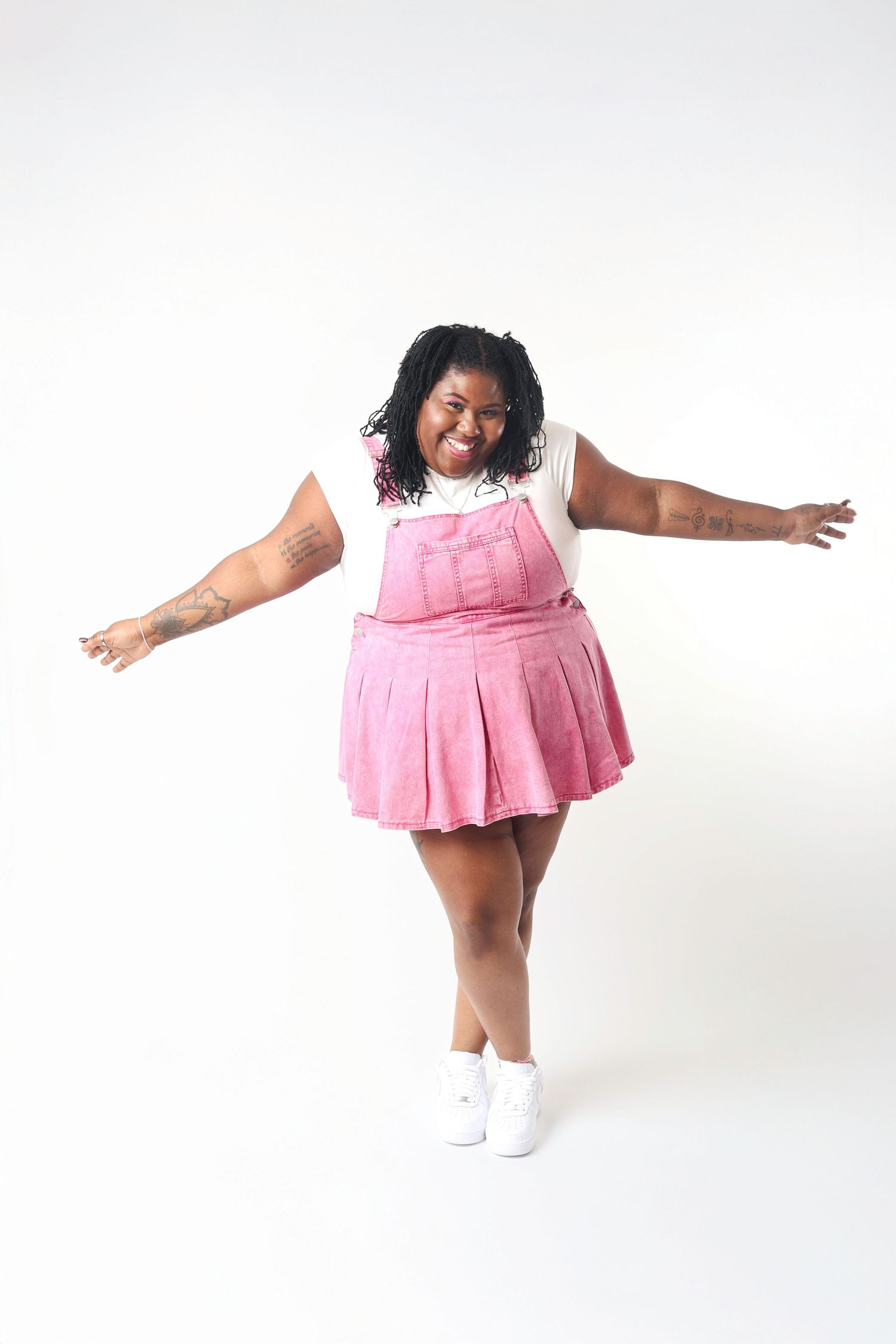 A child in a pink dress and white socks dances joyfully against a white background.