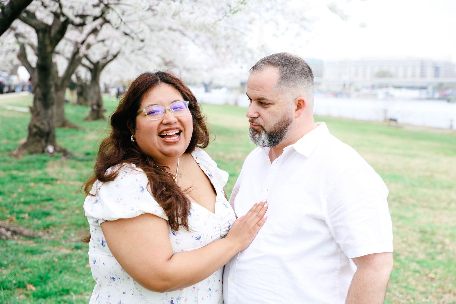 A couple shares intimate moments together outdoors during a joyful photo session in a park setting.