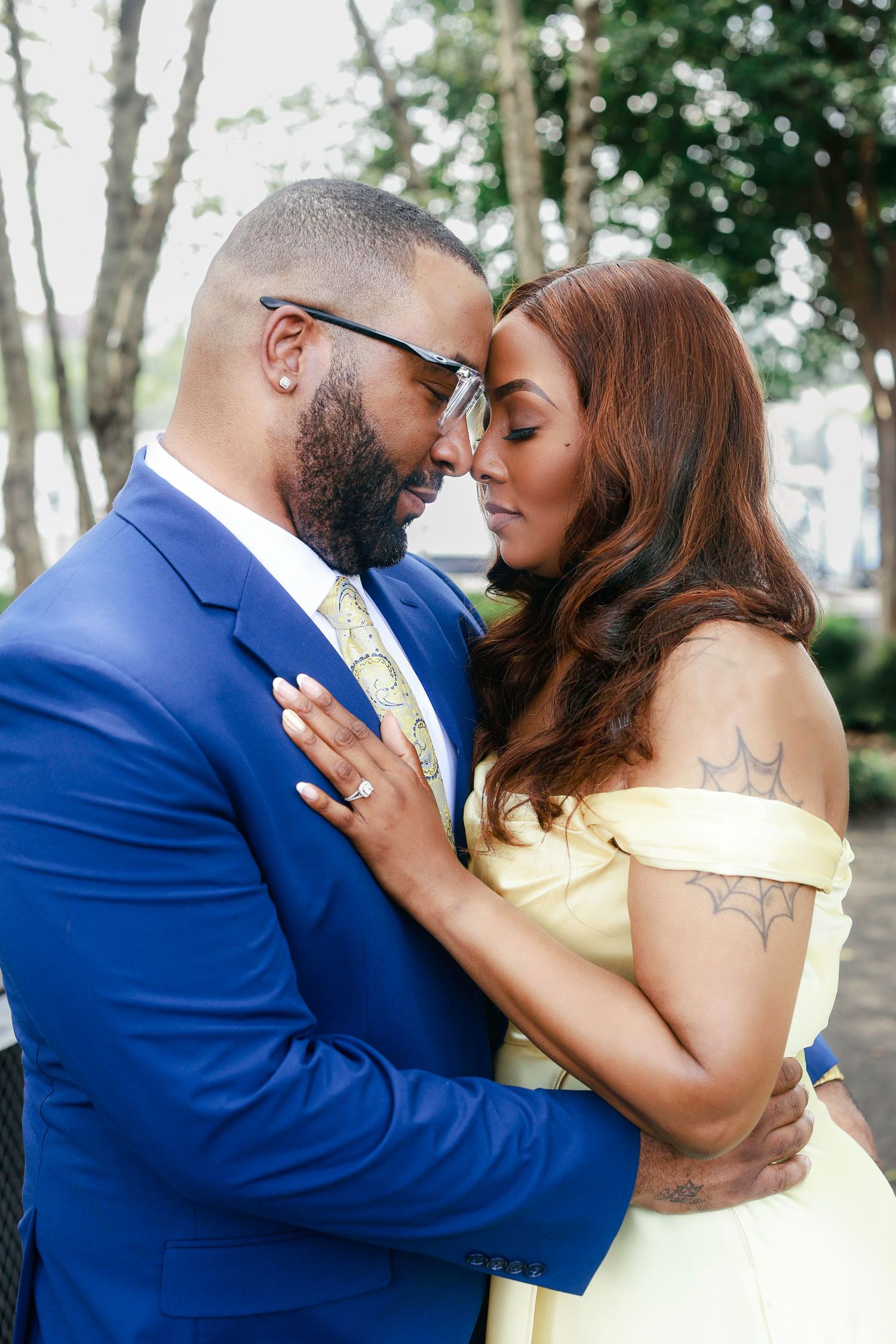 A romantic couple shares five intimate kisses while dressed in formal blue and yellow attire in an outdoor setting.