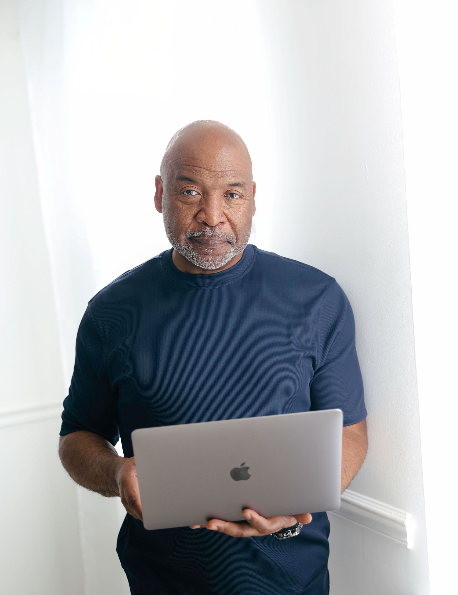 A person in a black t-shirt works on a MacBook laptop against a white background.