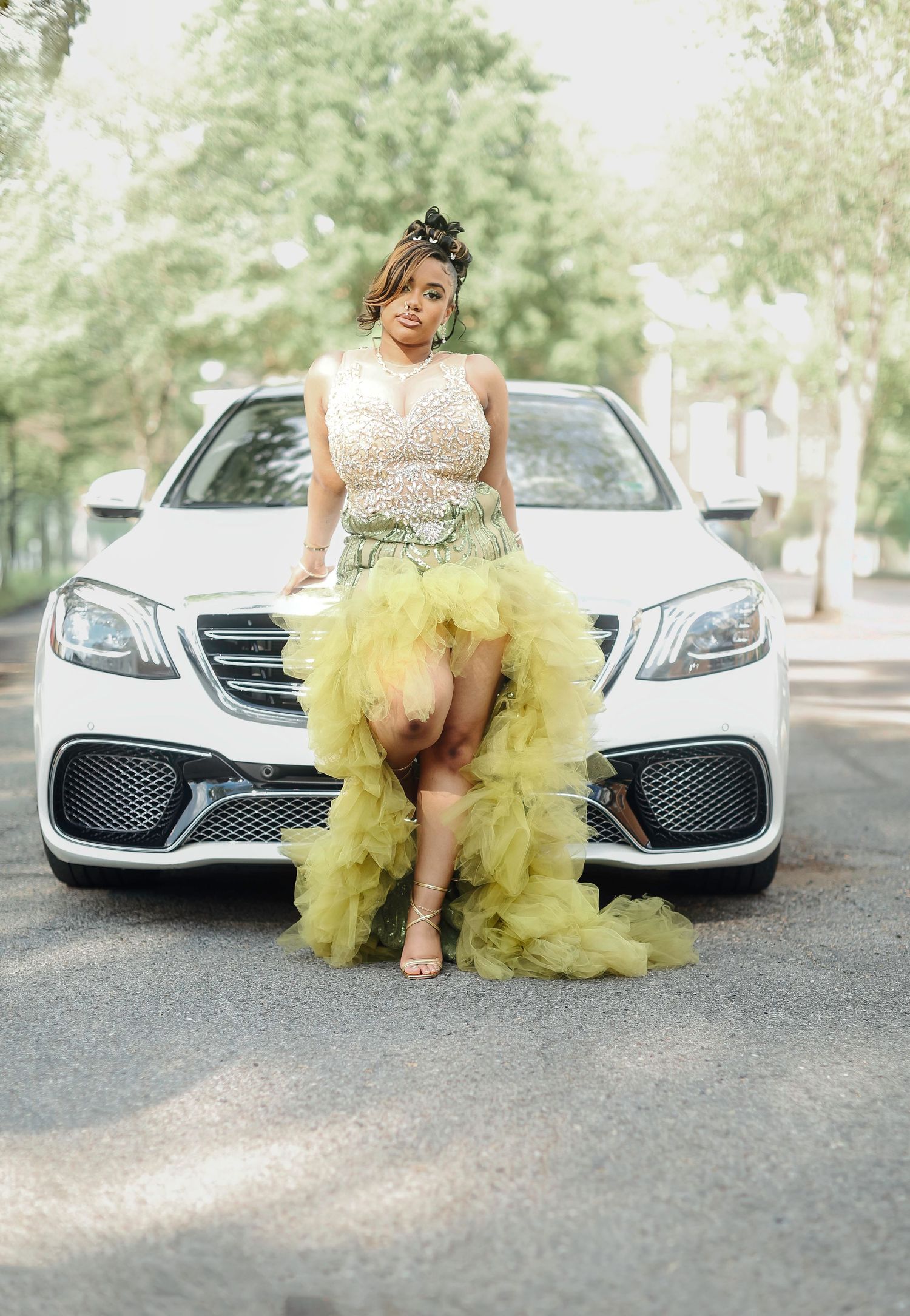 A luxurious yellow tulle dress photographed with a silver Mercedes-Benz car in an outdoor setting.