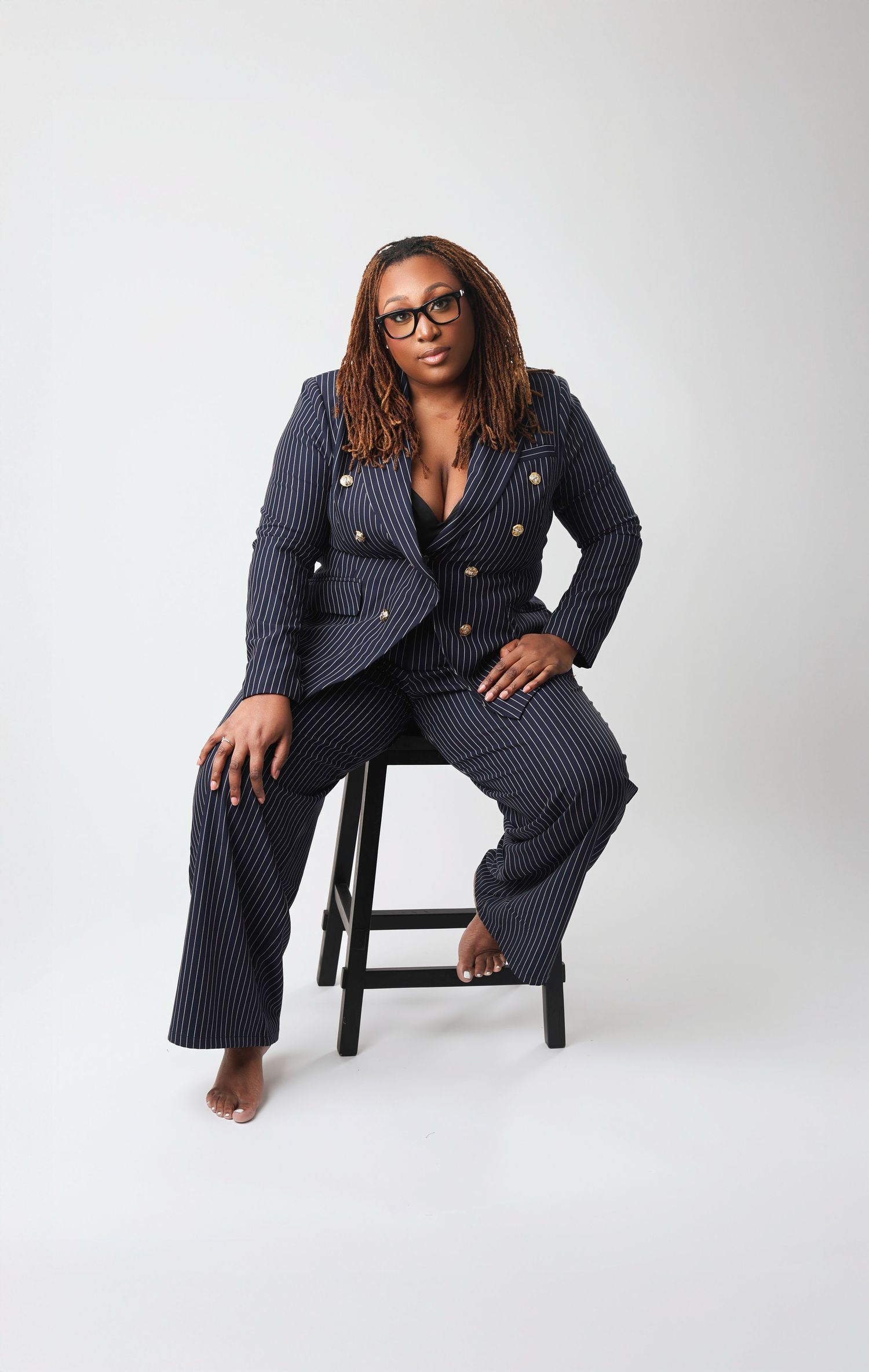 Professional fashion photo series showing a navy pinstripe power suit styled on a white studio backdrop with modern poses.