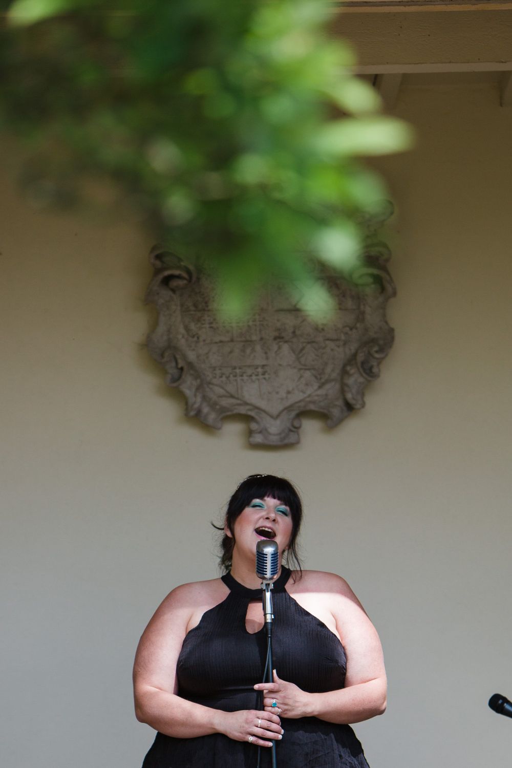 A performer in a black dress sings into a microphone at Tangled Garden wedding venue, Nova Scotia wedding photographer