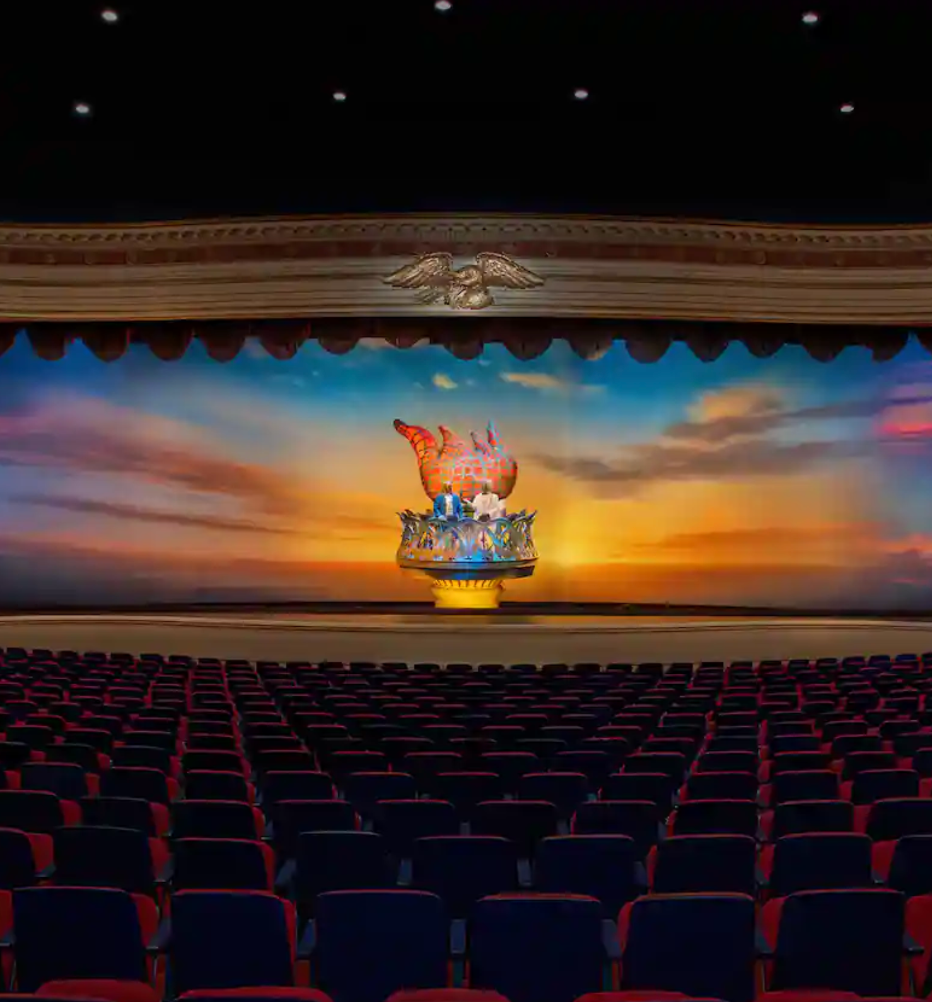 Dark movie theater auditorium with rows of red seats illuminated by cinematic lighting and projection screen in front.