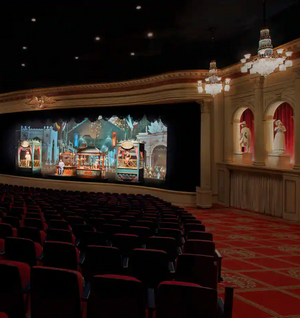 Interior view of empty theater showing rows of red seats and ornate architectural details in a historic performance venue.