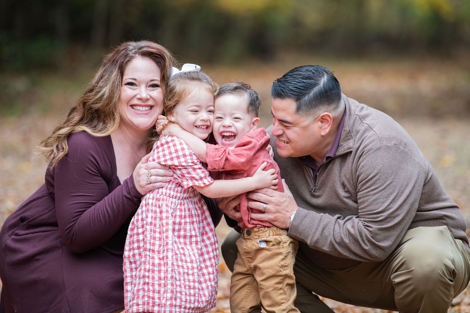 Young parents with their happy twins, enjoying the fall season with a beautiful, natural, and colorful background.