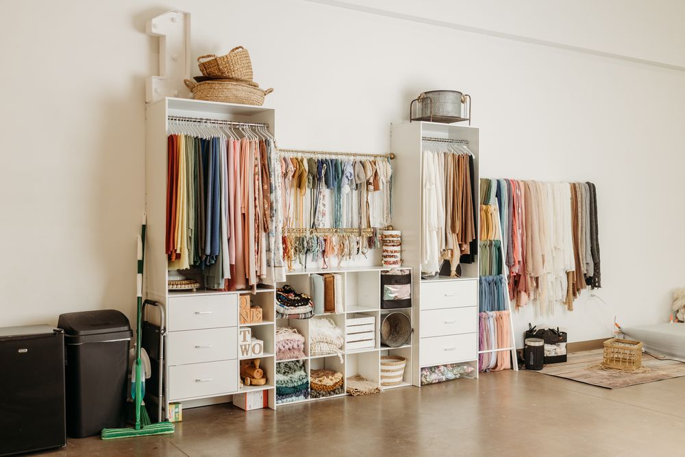 Organized clothing rack display with colorful garments, accessories, and storage cubbies in a bright retail studio space.