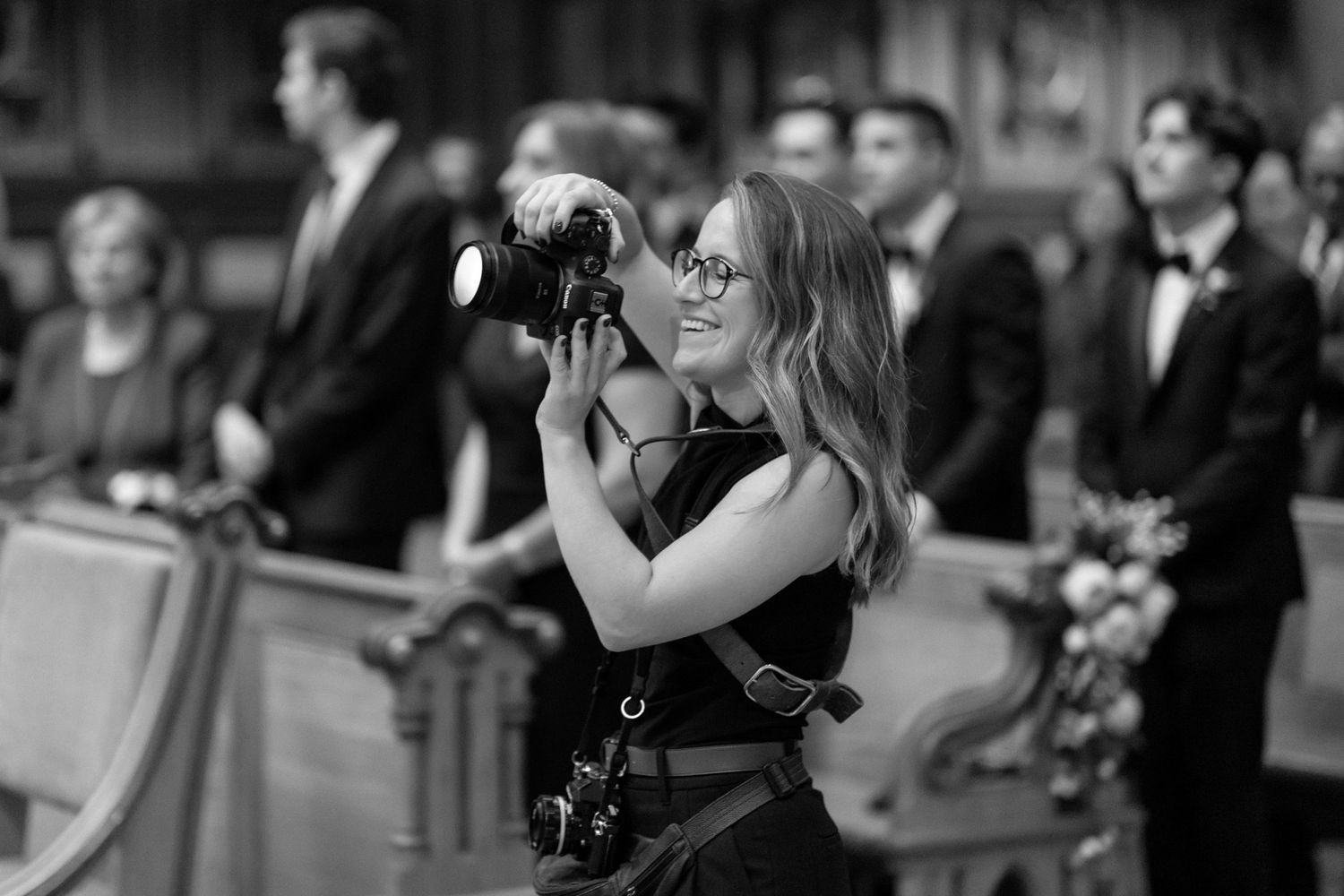 Black and white photo of photographer with professional camera documenting formal event.
