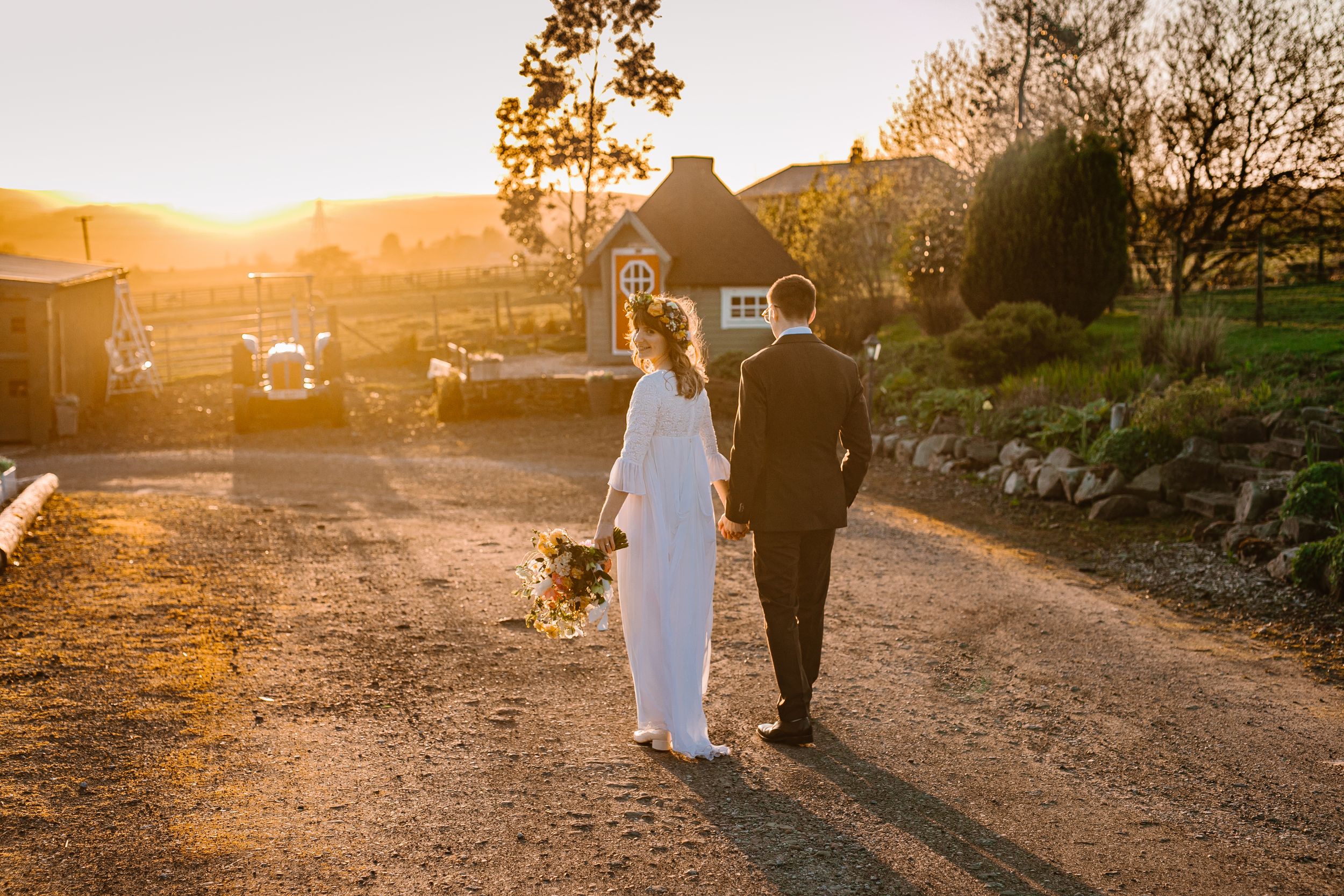 bride and groom walk into a golden sunset at the wellbeing farm