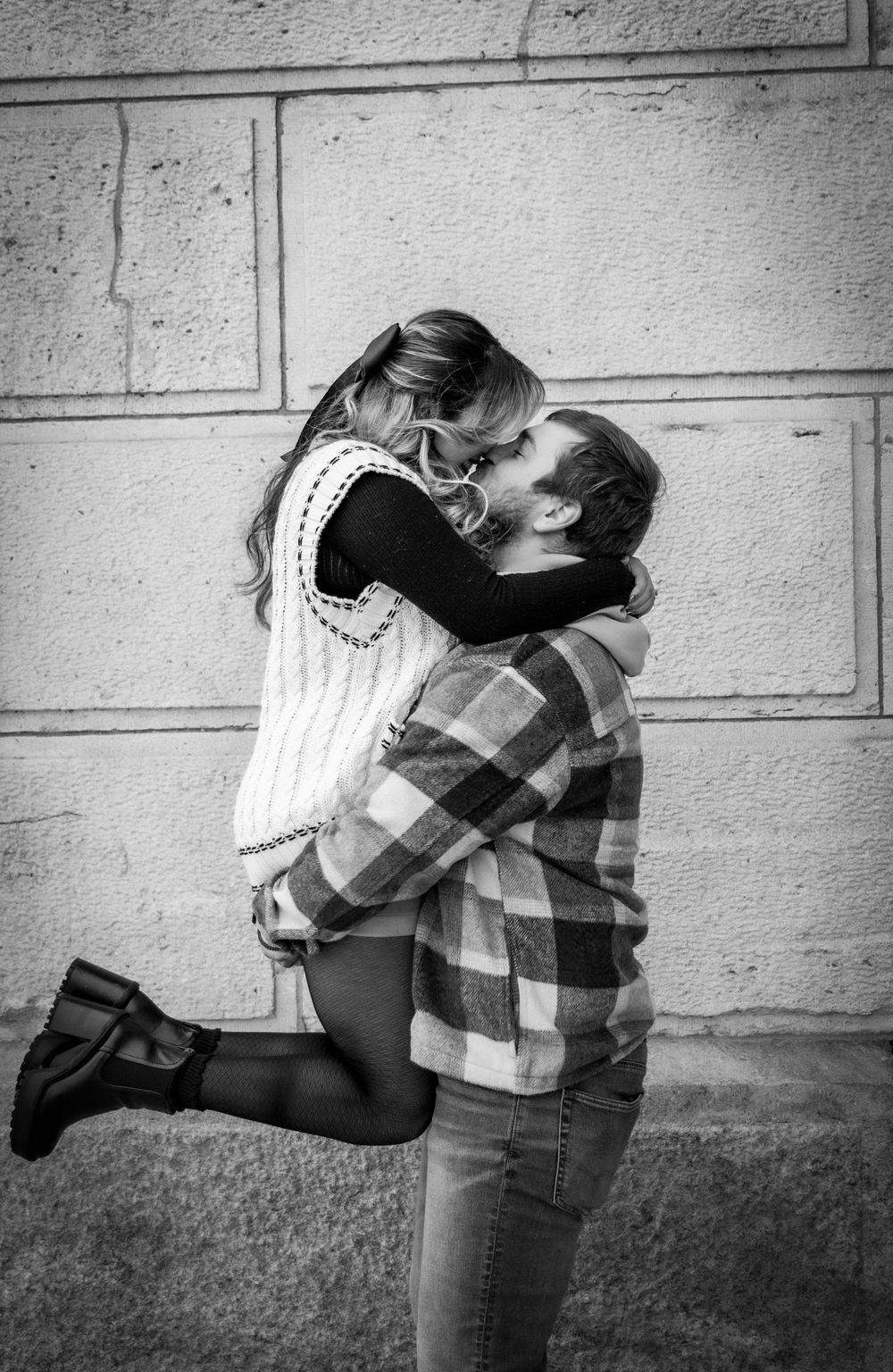 Man picking up fiancé at their engagement shoot on the Iowa State Capital Building grounds in the winter.