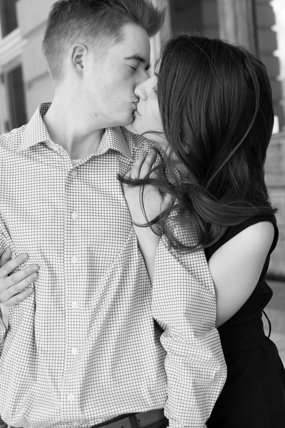 Engaged couple kissing by the front doors outside the Iowa State Capital.