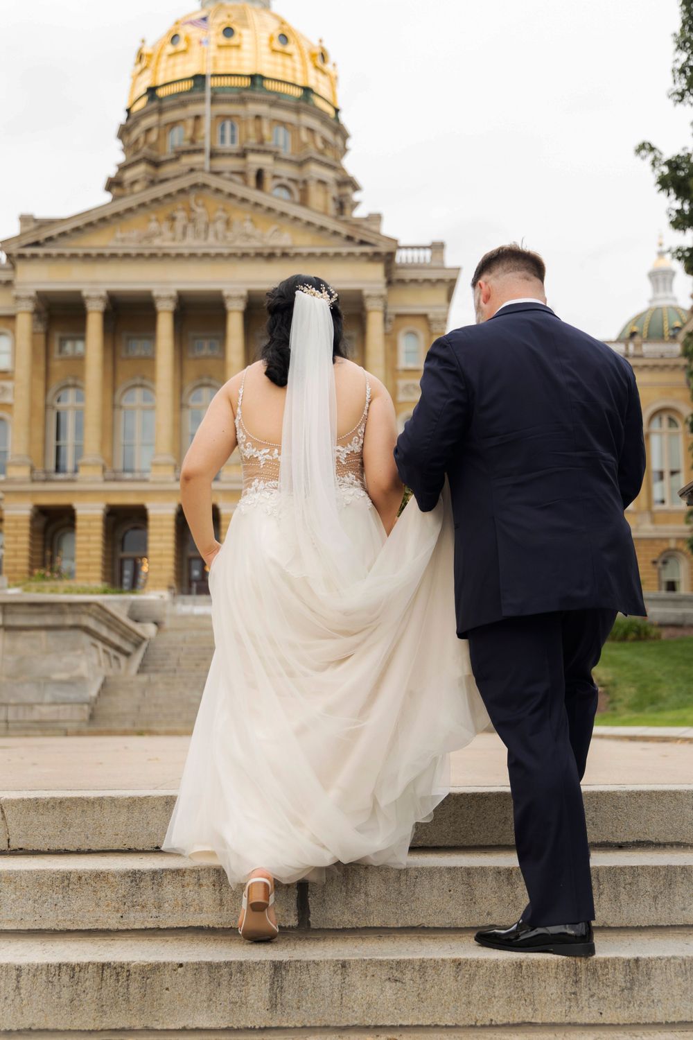 Bride and Groom walking up the stairs on the Iowa Capital grounds.