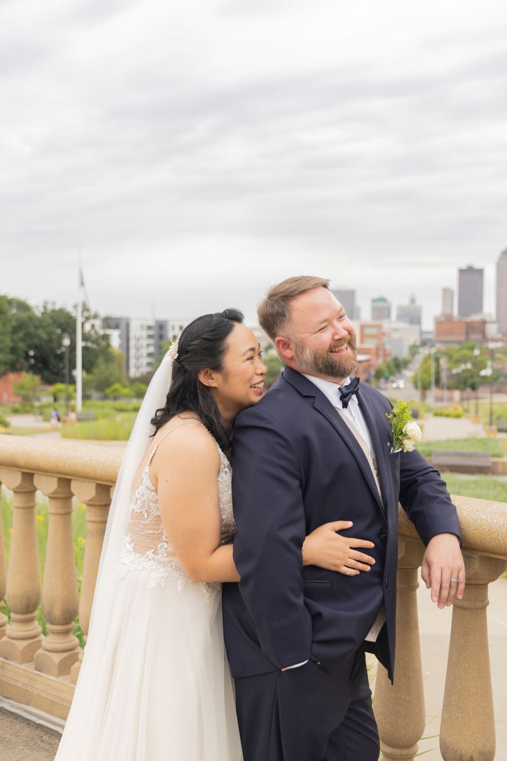 Bride and Groom looking off terrace at the city view on the Iowa State Capital grounds.