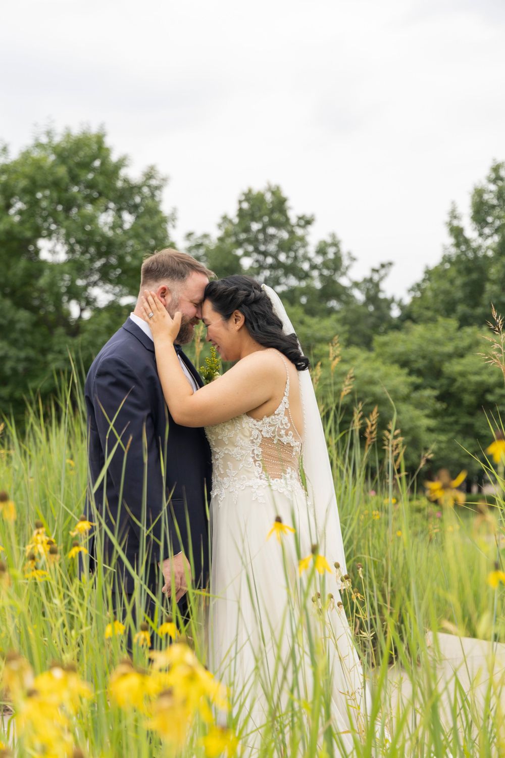 Bride and Groom touching foreheads in the wild grasses on the capital lawn.