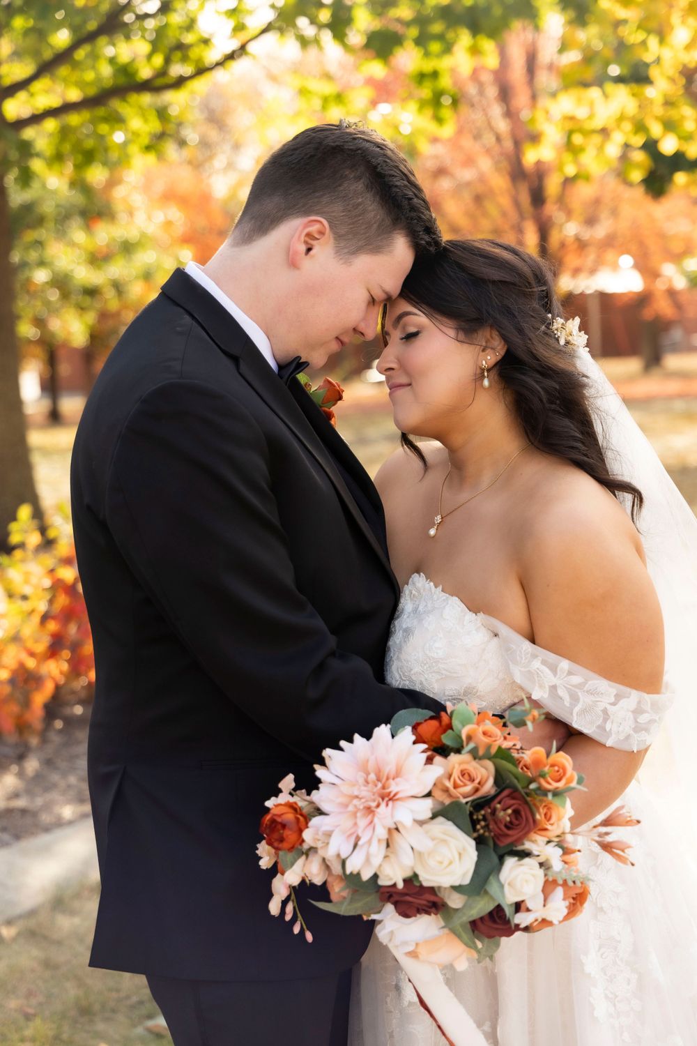 Married couple touching foreheads during their wedding pictures with A.West Photography on the Iowa State Capital lawn.