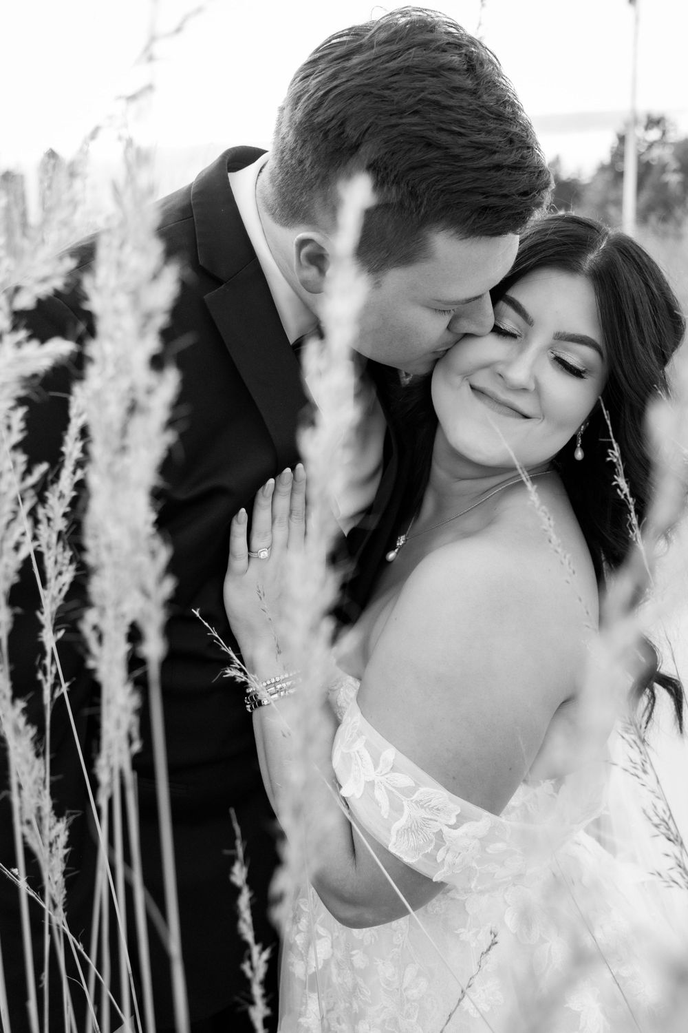 Groom kissing bride's cheek at the Iowa State Capital grasses on the front lawn.