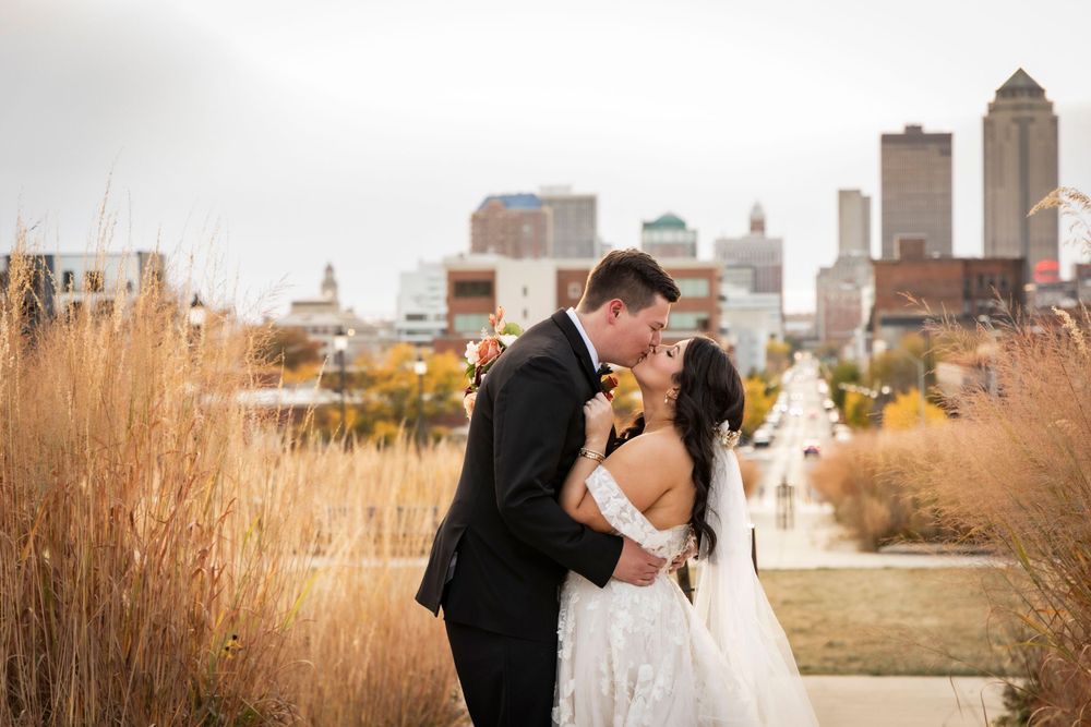 Bride and Groom kissing on the Iowa State Capital grounds with the city view in the background.