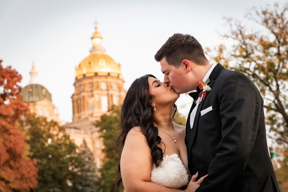 Bride and Groom kissing at sunset in the fall in front of the Iowa State Capital Building.