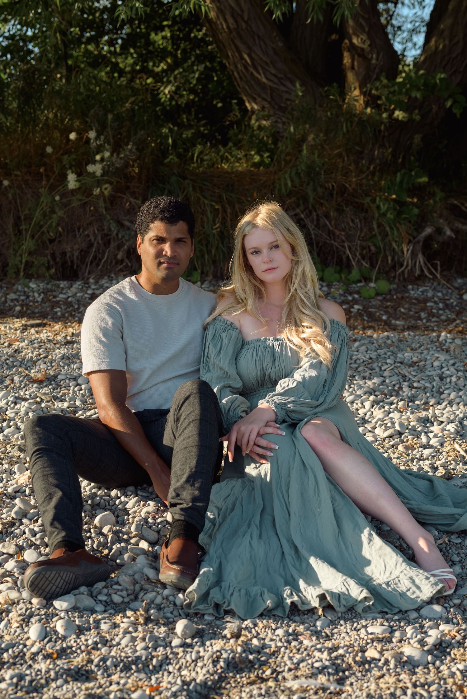 Couple posing on a sandy beach, facing the camera and holding each other.