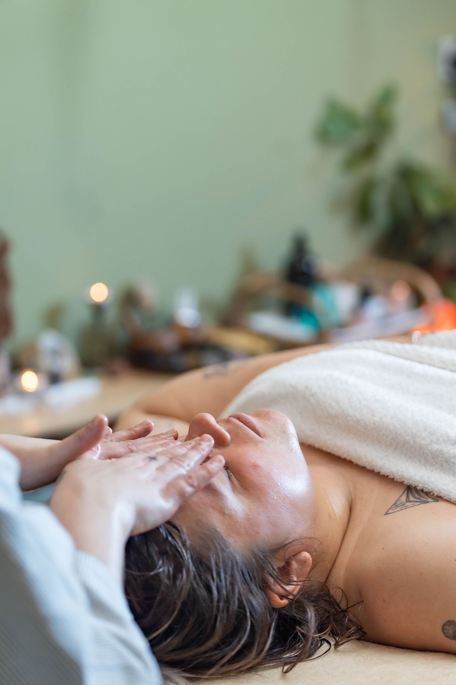 Holistic facial therapist performing a facial treatment in a peaceful, serene studio. The therapist is focused and gently applying skincare