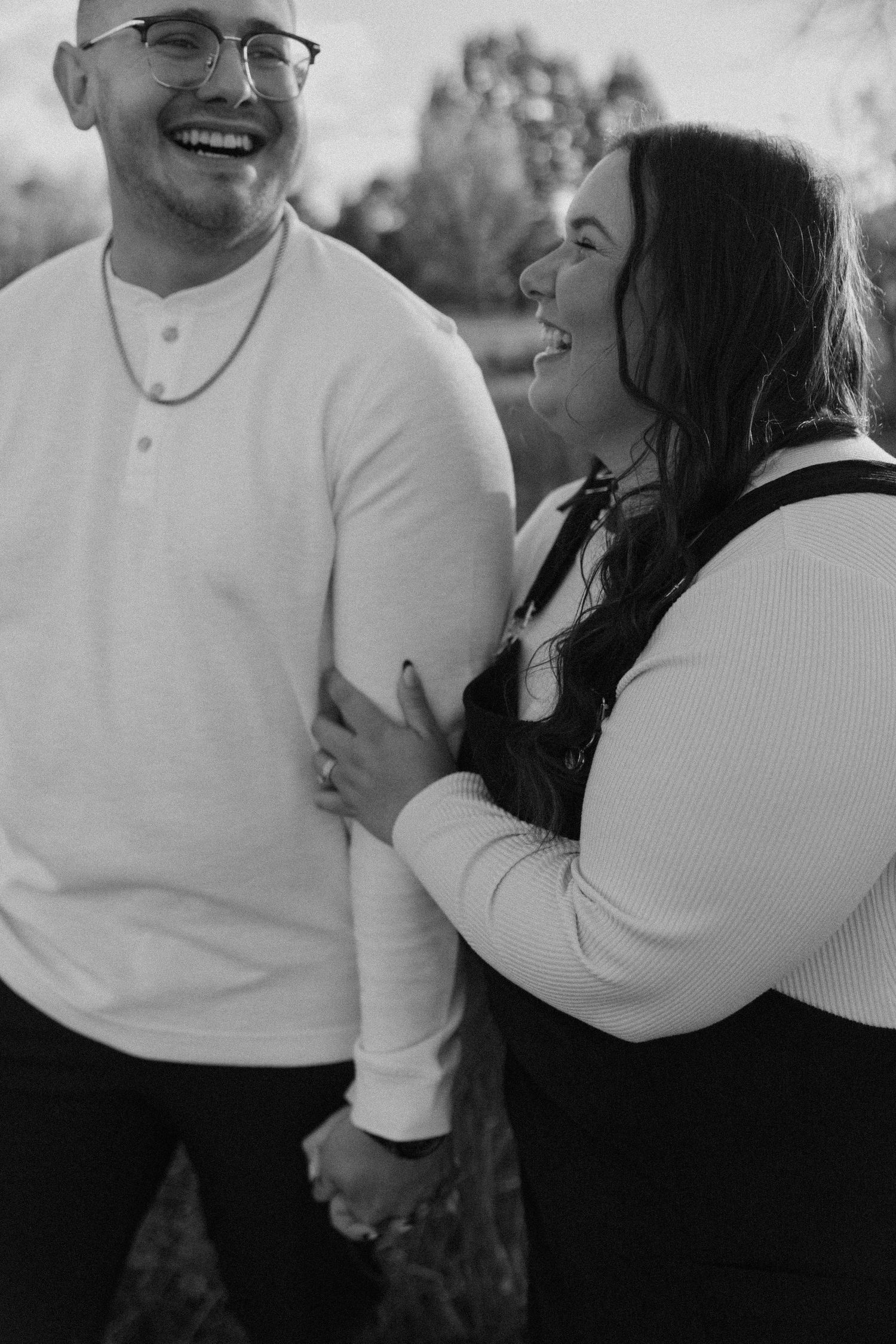 A candid black and white photograph capturing a joyful laughing moment between two people.