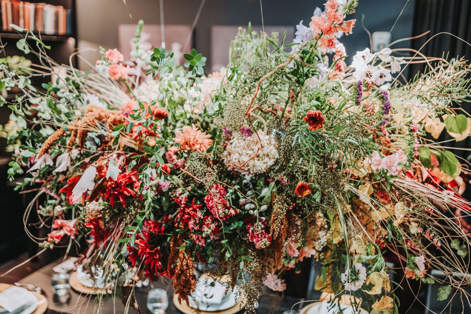 A lush floral arrangement with red berries, pink flowers and delicate foliage in vases on a wooden surface.  Located at the Canopy Hotel.