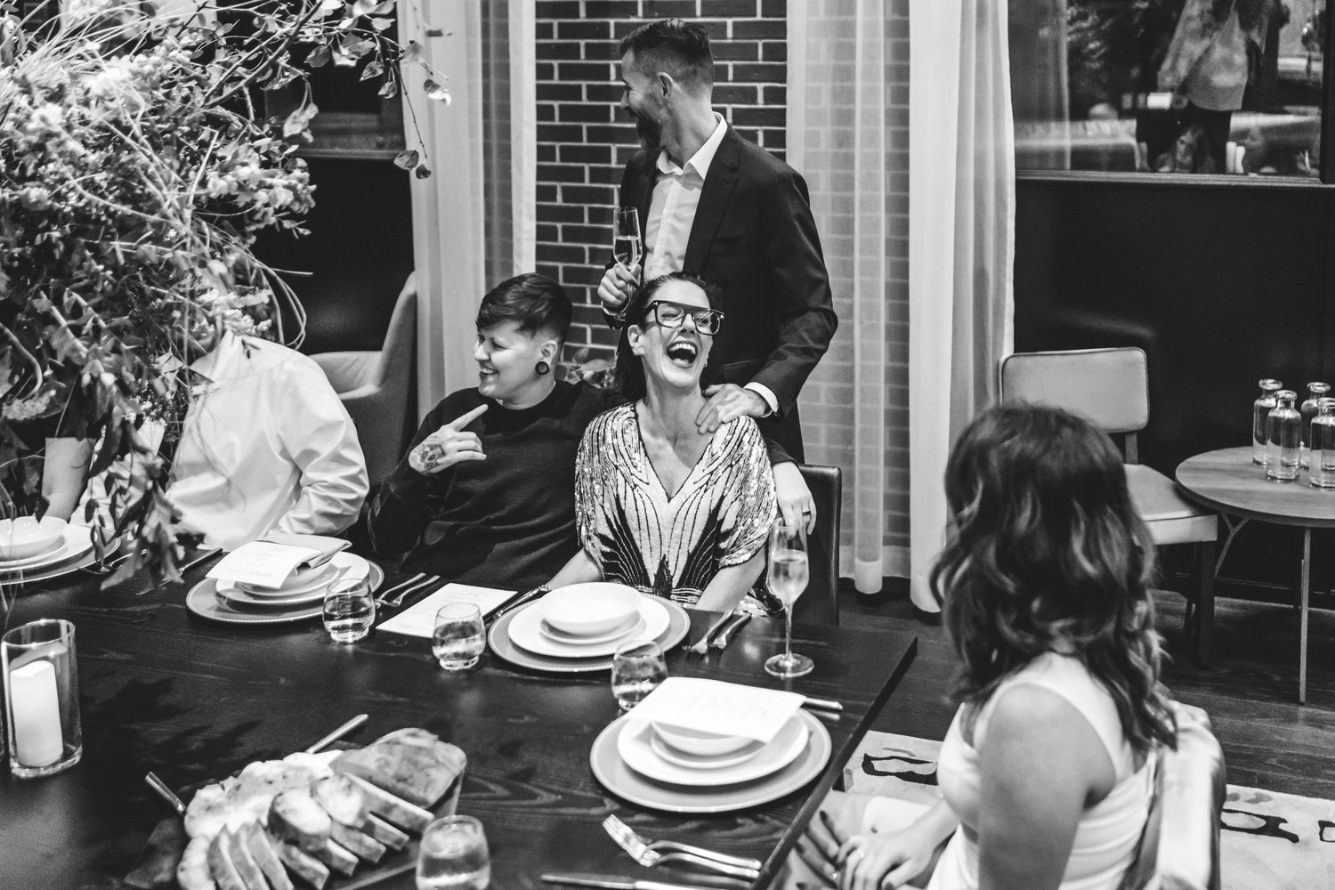 A black and white photo of a group dining together at a restaurant table located in the Canopy Hotel in Portland, Maine.