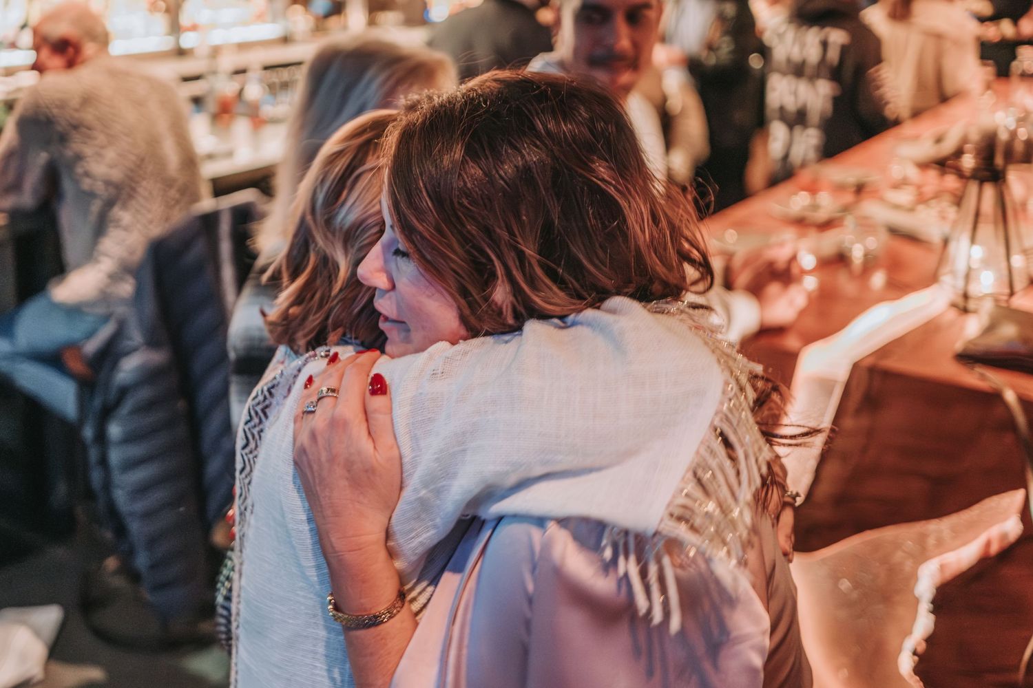 Two people share an emotional embrace during a post rehearsal dinner gathering.  The bride-to-be is happy to see the wedding guests.