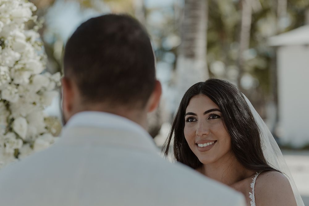 Couple exchanges intimate vows during beautiful outdoor wedding ceremony surrounded by white floral arrangements.