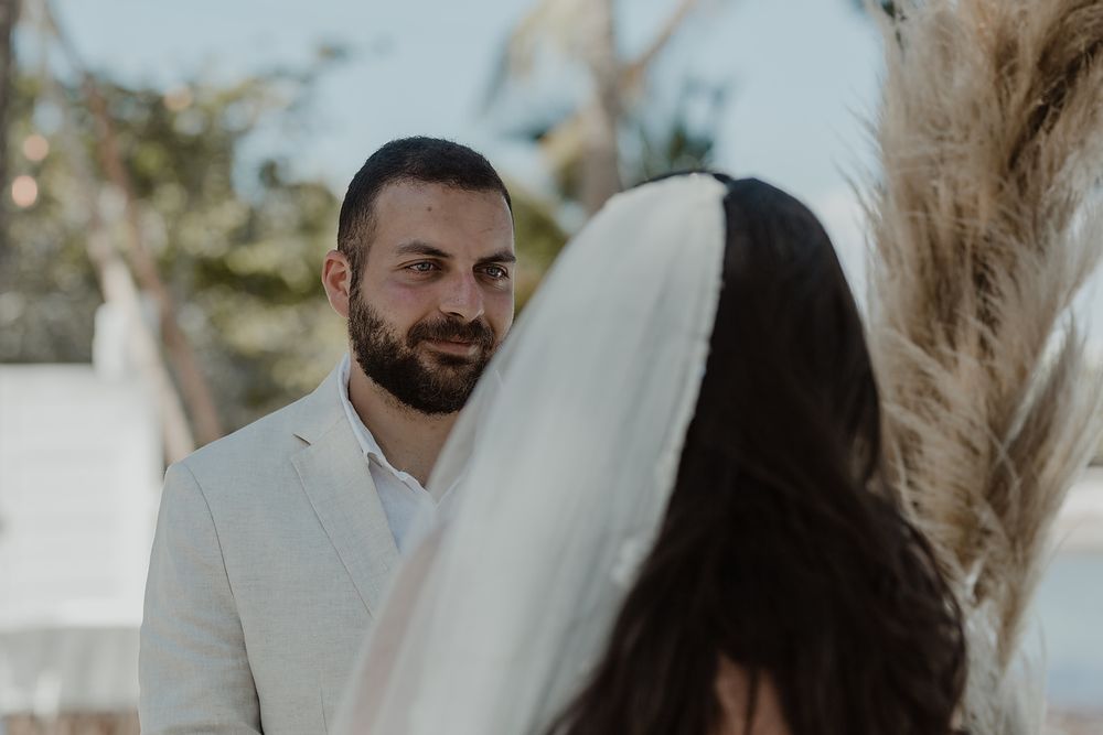 A tender moment between newlyweds during an outdoor wedding ceremony, with the groom wearing a light beige suit.