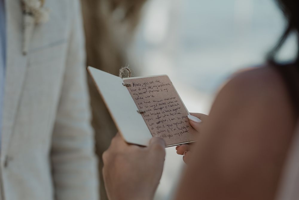 Close-up view of hands holding handwritten vows or letter during an intimate wedding ceremony.