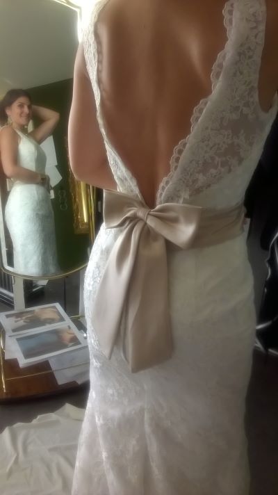Rückenansicht eines Brautkleids mit tiefem Rückenausschnitt und einer beigen Masche am Rücken