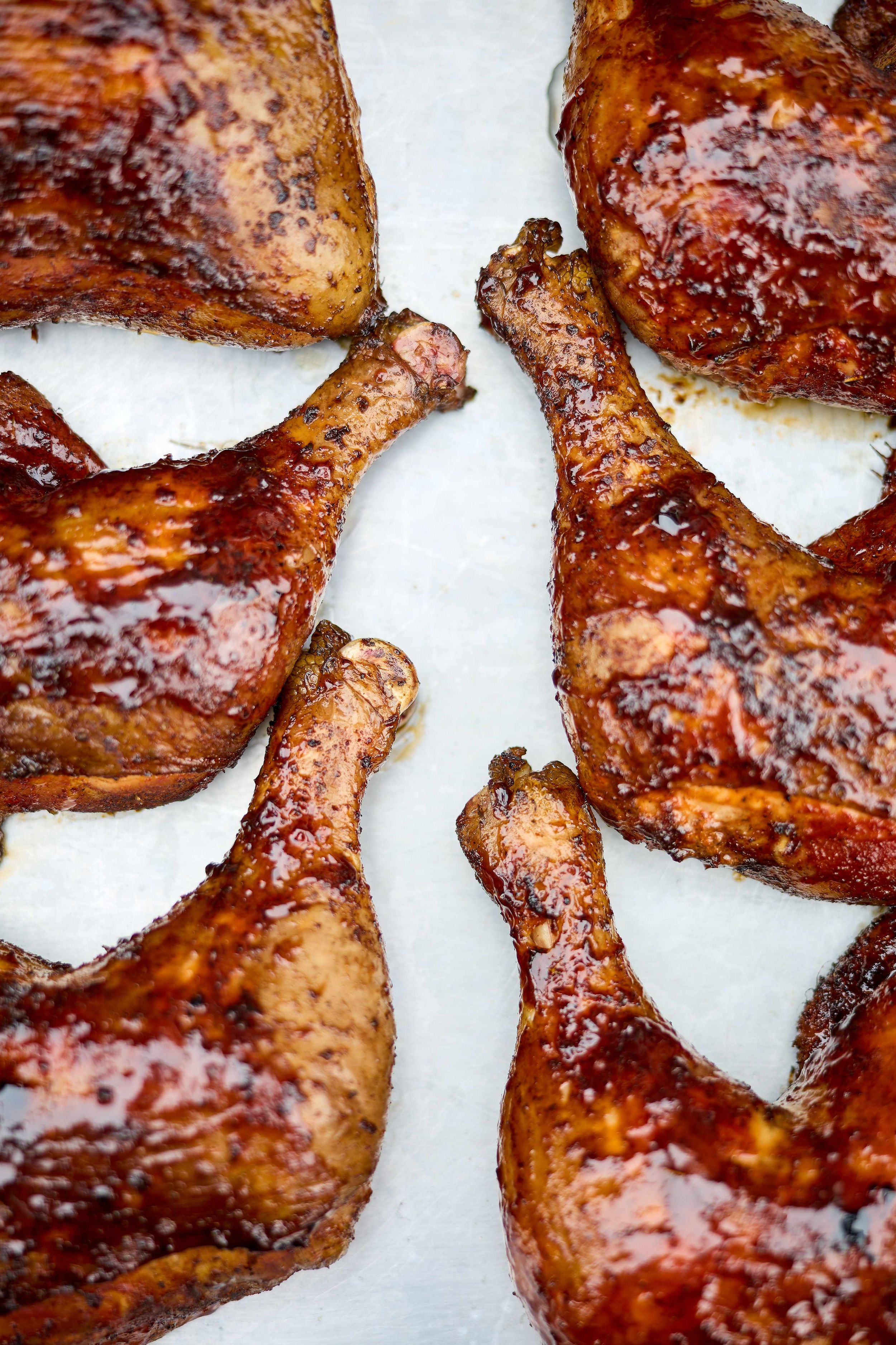 A food photo of smoked BBQ chicken from above on a white backdrop