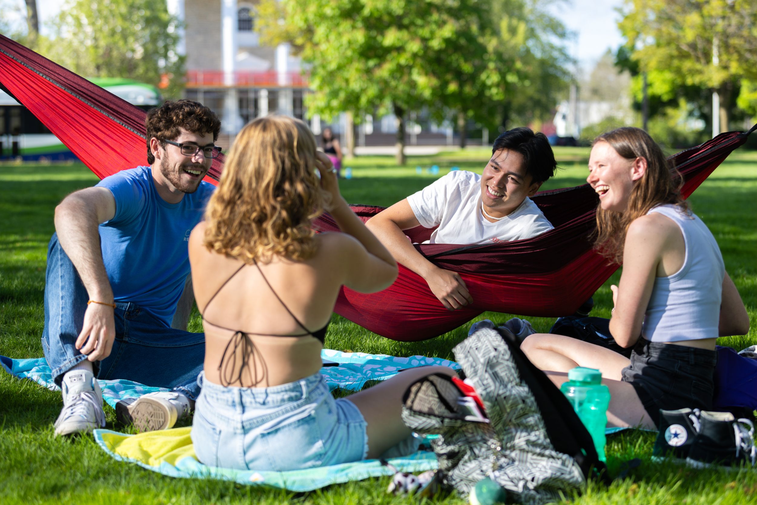 Students sit in hammocks and on blankets in the spring weather.