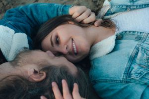 Intimate couple portrait lying down in denim jackets outdoors.