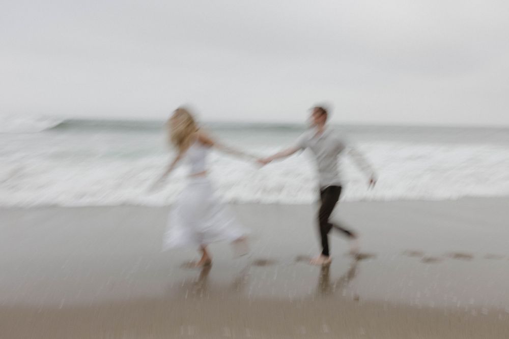 A blurred artistic shot of a couple dancing on the beach at dusk.