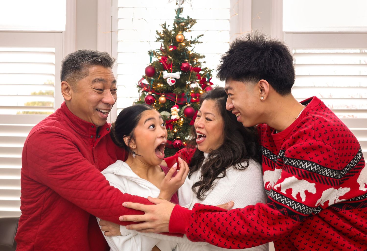 Family around a Christmas tree in an embrace laughing at each other