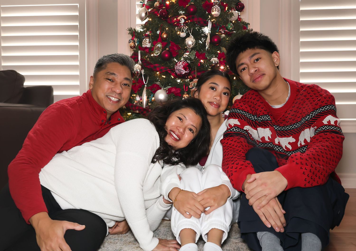 Family around a Christmas tree posing for a photo being silly