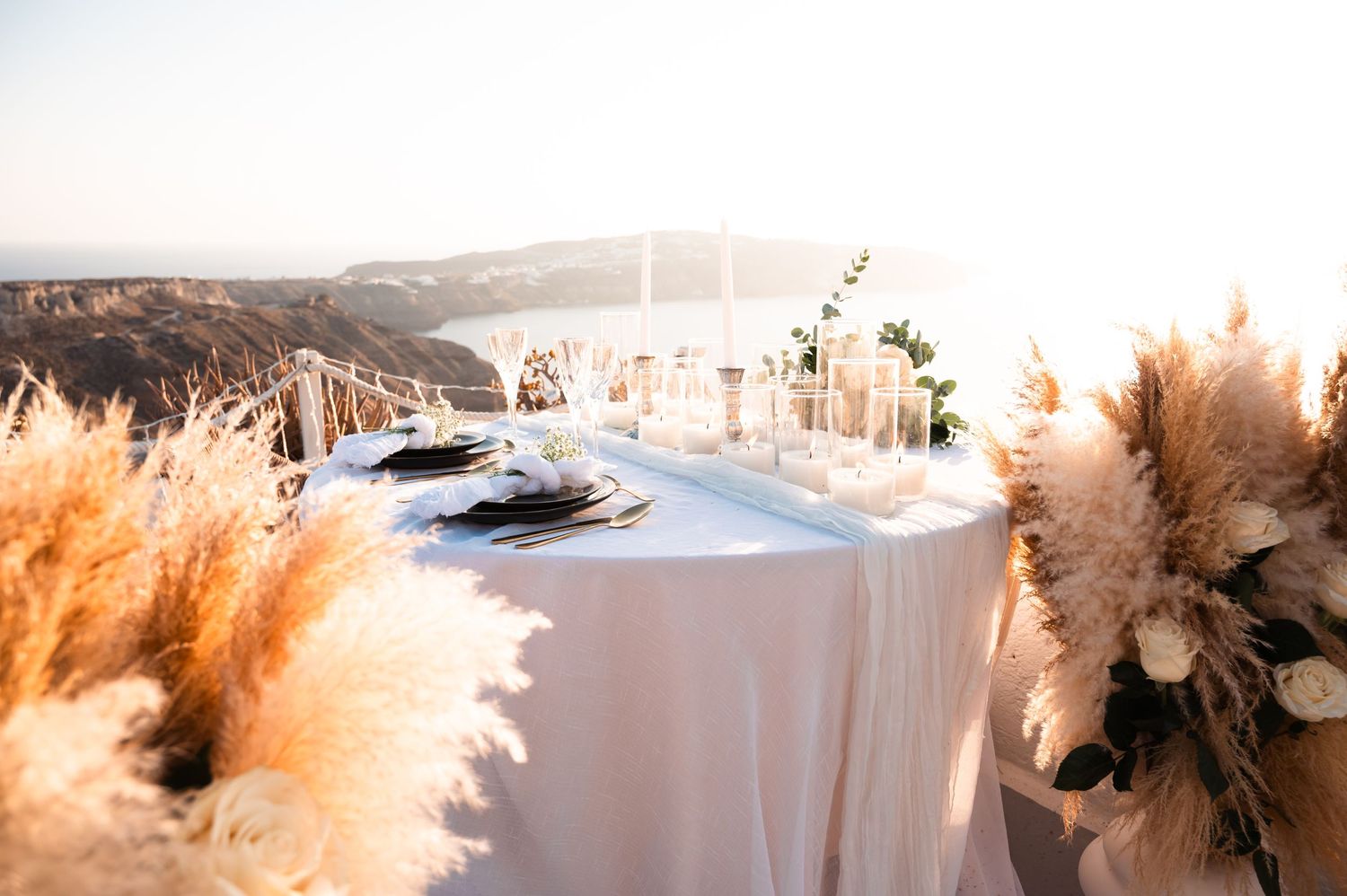 Elegant wedding reception table with pampas grass decor overlooking Mediterranean sunset.